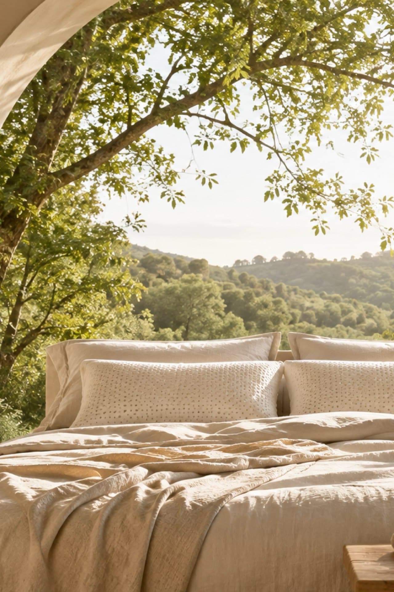 Una cama tendida bajo un arco, con la luz de la mañana sobre las montañas